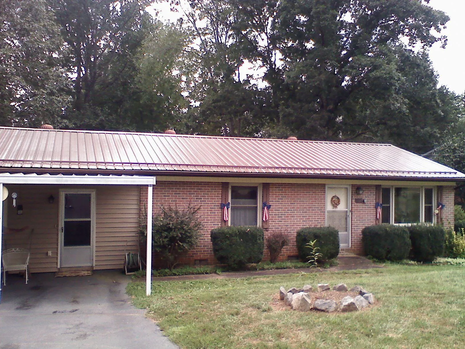 Bronze metal roof and carport on a brick ranch home — Roof Repair work by our crew in Dexter