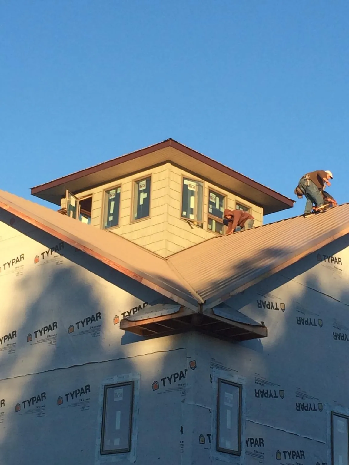 Roofers working around a rooftop cupola on a new metal roof at sunset — Roof Waterproofing in Dexter by Roofing Brothers